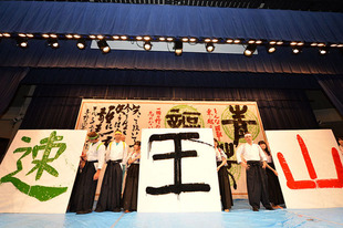 県立与野高校の書道部の手ほどきで選手が書道を体験。袴とハチマキ姿で獲得した賞を表す文字を表現。