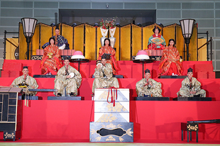 さいたま市出身の村田綾さんがお雛様、岩槻商業高校ソフトボール部の3名が三人官女に扮し、豪華な岩槻の人形ジャンボひな壇を再現